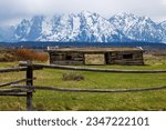 J. Pierce Cunningham cabin and lodge pole fence in Grand Teton National Park, Wyoming. With csnow covered mountains in the background. 