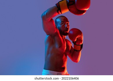 Jab, hook. Young sportsman, professional boxer in gloves training on purple neon background. Health, professional sport, motion concept. Copy space for advertisement - Powered by Shutterstock