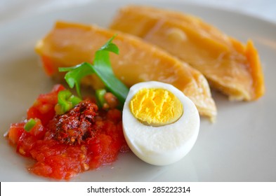 Jachnun, Yemenite Jewish pastry, served with fresh grated tomato and skhug and boiled egg, on Shabbat morning in Israel. Food background and texture