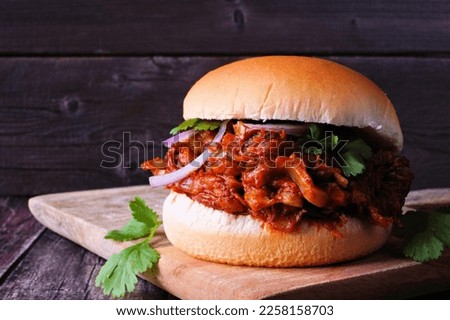 Jack fruit meatless burger against a dark wood background. Healthy eating, plant-based pulled pork meat substitute concept.