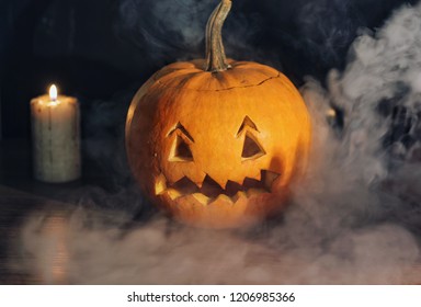 Jack o'lantern, thick smoke and candles on the black background, decor for Halloween