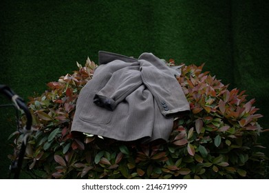 Jacket Left On A Bush With A Green Background.