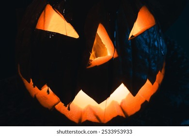 A jack-o'-lantern with a glowing face sits in a dark, smoky room lit by a blue light. - Powered by Shutterstock