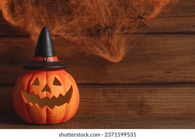 Jack-o-latern against the background of cobweb with two spiders. Halloween postcard. Selective focus, copy space for text
