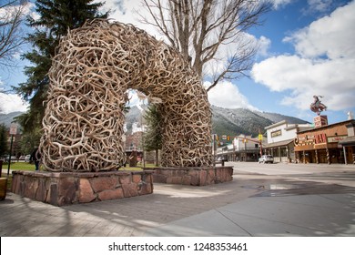 Jackson Hole, Wyoming / USA - April 4 2016: Famous Antler Arch at Jackson Town Square, with Cowboy Bar and ski slopes in the background