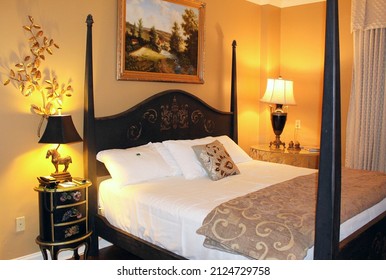 JACKSON, MISSISSIPPI, USA – JULY 25: Antique bed flanked by nightstands and lamps with wall painting and art at Old Capitol Inn on July 25, 2015.