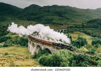 Jacobite steam train crossing the Glenfinnan Viaduct with steam rising from the chimney. Hogwarts Express, Harry Potter. - Shutterstock ID 2254429181