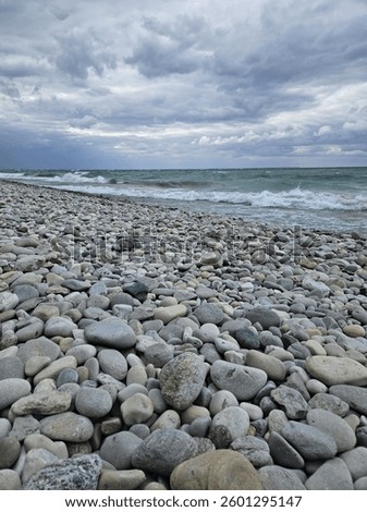 The jade-colored waves lap the rocky beach under the cloud-covered sky at Peterson Park in Northport, Michigan.