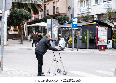 JAEN, SPAIN - Jan 25, 2022: A Elderly Man Crossing The Street With A Walker In The City Of Jaen