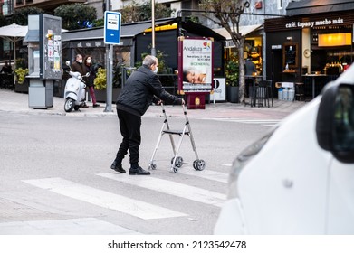 JAEN, SPAIN - Jan 25, 2022: A Elderly Man Crossing The Street With A Walker In The City Of Jaen