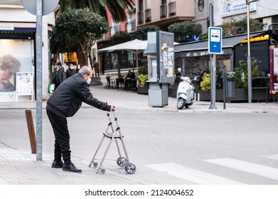 JAEN, SPAIN - Jan 25, 2022: A Elderly Man Crossing The Street With A Walker In The City Of Jaen