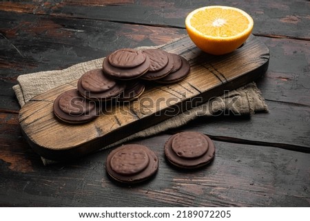 Jaffa Cakes. Cookies covered with dark chocolate and filled with orange marmalade set, on old dark  wooden table background