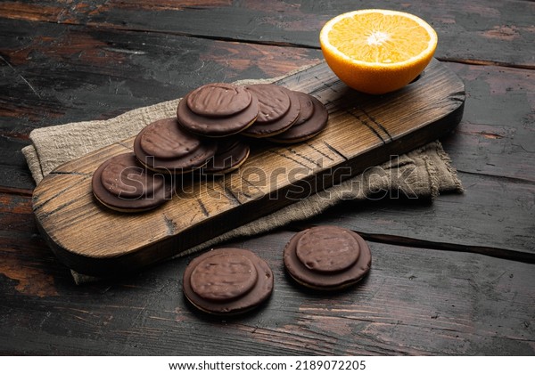 Jaffa\
Cakes. Cookies covered with dark chocolate and filled with orange\
marmalade set, on old dark  wooden table\
background