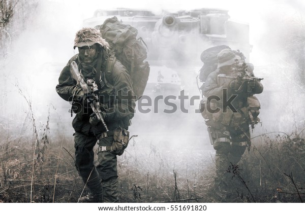 Jagdkommando soldiers Austrian special forces and tank moving on terrain in the fog. They are ready to face the enemy. NATO military power concept