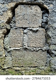 The jagged, lighter-colored outer wall acts as a natural border that draws the viewer’s eye directly to the central subject: the dark, rectangular stone blocks. The vertical alignment of the stones creates a sense of grounded stability.