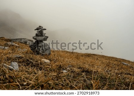 Jagged Rock Cairn Marks The Eiger Trail In The Swiss Alps on Foggy Autumn Day