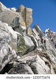 Jagged Rock And Snow Mountain Ridge With Three Mountain Climbers In The Background