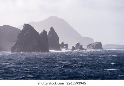 Jagged rocky outcroppings off Hornos Island with Cape Horn in distance