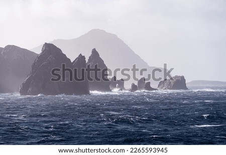 Jagged rocky outcroppings off Hornos Island with Cape Horn in distance