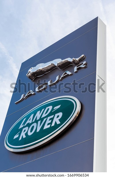 Jaguar Land Rover brand logo on bright blue sky\
background located on its dealer office building in Lyon, France -\
February 23, 2020