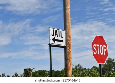 Jail Sign With A Black Arrow Next To A Stop Sign