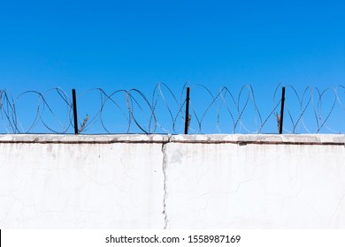 Jail wall. Highly protected prison wall with barbed wire fence. Blue sky background with copy space