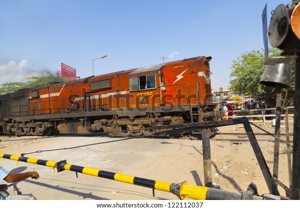 JAIPUR, INDIA - OCT 23: Indian Railway train\
passes a railroad crossing on Oct 23, 2012 in Jaipur, India. Indian\
Railways is one of the worlds largest railway networks comprising\
115000 km of track.