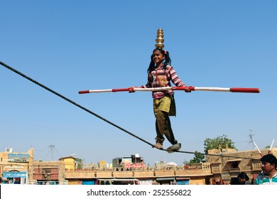 JAISALMER, INDIA - FEB 03, 2015: An unidentified Indian girl performs street acrobatics by walking the rope during the Desert Festival on February 03,2015 in Jaisalmer, Rajasthan, India.