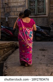 Jaisalmer, India - October 30 2020 : Loving Asian Indian Woman Walks With Her Sleeping Child On Her Shoulder, Woman Carrying Her Sleeping Child On Her Shoulder To Home Passing From The Streets