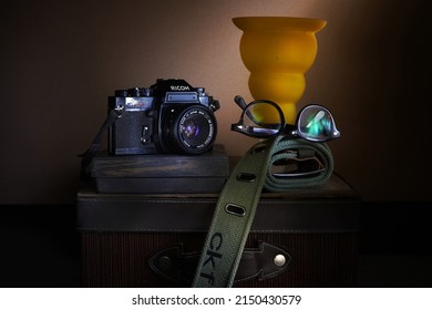 Jakarta, 27 April 2022. Still life photography with good composition, using Light Painting technique. Old camera, placemat, other accessories and blurred background.                               