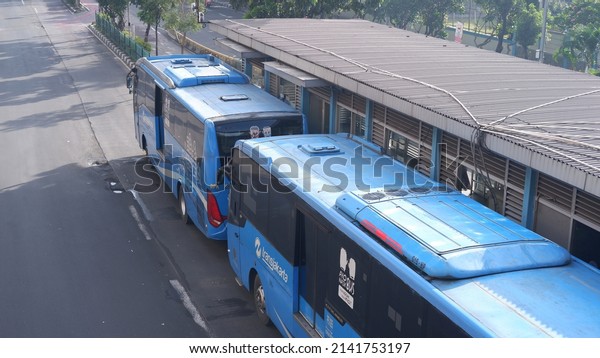 Jakarta, Indonesia - April 02, 2022: Transjakarta bus is\
picking up and dropping passengers at a bus stop, Transjakarta is\
biggest land transportation company in Jakarta owned by Jakarta\
government 