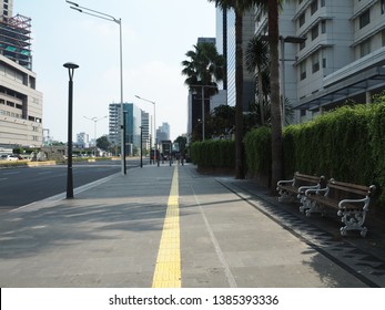 Jakarta, Indonesia - April 17, 2019: Pedestrian sidewalk on Thamrin street with background of modern tall buildings.