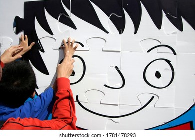 Jakarta, Indonesia
April 2, 2011.

An Autism Child Helped By His Caregiver To Arrange Giant Puzzle.