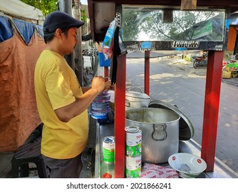 Jakarta, Indonesia, August 2, 2021 a seller of green bean porridge and black sticky rice, tukang bubur kacang ijo dan ketan item, is peddling his food on the side of the road from his cart or gerobak.