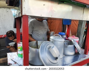Jakarta, Indonesia, August 28, 2021, a green bean and black sticky rice porridge vendor or tukang bubur kacang ijo dan ketan item prepares his food, from his food street cart or gerobak pinggir jalan