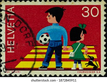 Jakarta, Indonesia - December 03, 2020: Old Helvetia Postage Stamp With An Illustration Of A Child Carrying A Football And A Dog.