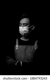 JAKARTA, INDONESIA - DECEMBER 2020: Service Minded Handsome Smiling Asian Barista Serving Coffee Studio Shot Isolated On Black Background