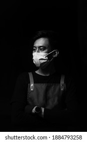 JAKARTA, INDONESIA - DECEMBER 2020: Service Minded Handsome Smiling Asian Barista Serving Coffee Studio Shot Isolated On Black Background