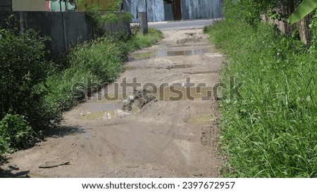 Jakarta, Indonesia - Descember 7, 2023: potholed dirt road in the countryside