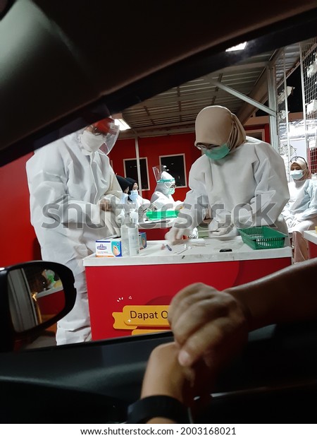 Jakarta, Indonesia -\
February 13, 2021 : Medical worker in protective suit screening\
driver to sampling secretion to check for Covid-19. Drive thru test\
coronavirus fast track