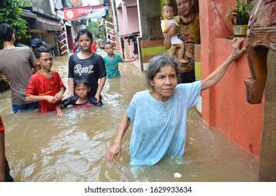 Jakarta, Indonesia - February 20, 2017 : A Grandmother Who Walks In A Flood And Holds The Walls Of A House