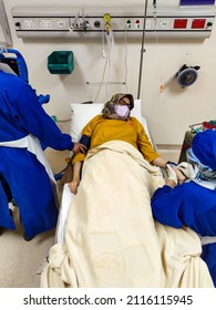 Jakarta, Indonesia - Jan 2022: Patient Laying On Bed Receiving Medical Treatment From Nurse With Blue Uniform In Intensive Care Unit Room At Hospital.