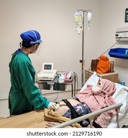 Jakarta, Indonesia - Jan 2022: Patient Laying On Bed Receiving Medical Treatment From Nurse With Green Uniform In Intensive Care Unit Room At Hospital.