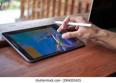 Jakarta, Indonesia - July 28, 2021: A Man Using Apple Pencil Drawing Cartoon Illustration On A IPad Using Procreate App.