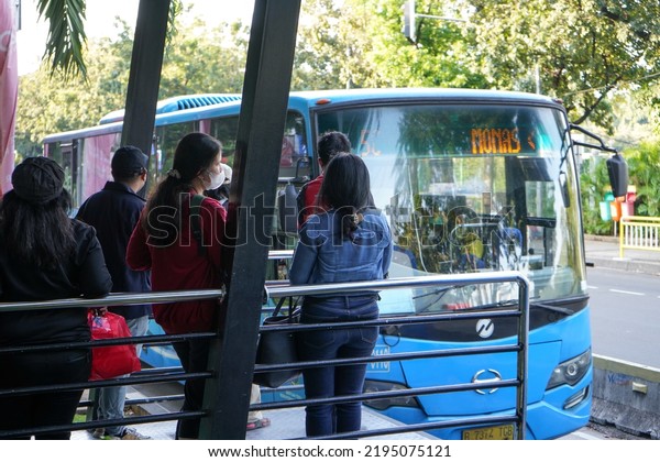 Jakarta, Indonesia - June, 2022 : \
The situation in\
the bus stop or Transjakarta bus terminal which is very crowded\
with workers going to the office. They lined up neatly waiting to\
enter the bus.