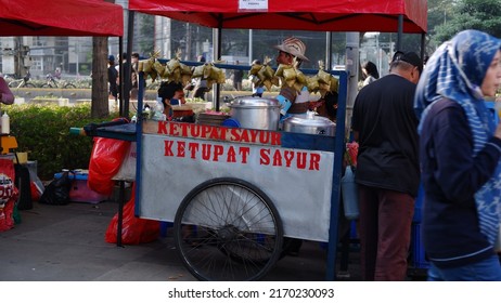 Jakarta, Indonesia - June 22, 2022: Ketupat sayur seller cart on the sidewalk.Ketupat sayur is a typical Indonesian rice cake made from rice wrapped in coconut leaves then boiled and served with curry