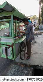 Jakarta Indonesia June 26, 2021 -  an asian man sells food on a green wooden cart, a typical Indonesian food called Lontong Sayur, this food contains rice cake with vegetable coconut milk sauce 