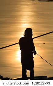 Jakarta / Indonesia - March 26, 2012 : 
Silhouette Of Fishermen With Reflected Sunlight At Sea Level - Morning At The Angke Pier