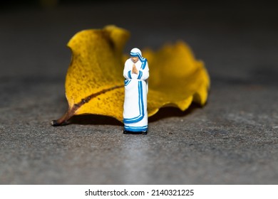 Jakarta - Indonesia - March 29, 2022: Mother Teresa mini figure doll standing against a yellow leaf background.