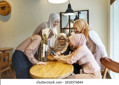 Jakarta, Indonesia - May 2016: Group Of Muslim Asian Women Friends Or Colleagues Wearing Hijab, Having A Business Meeting In Cafe. Looking At Smartphone Or Mobile Phone. Smiling, Happy Expression.